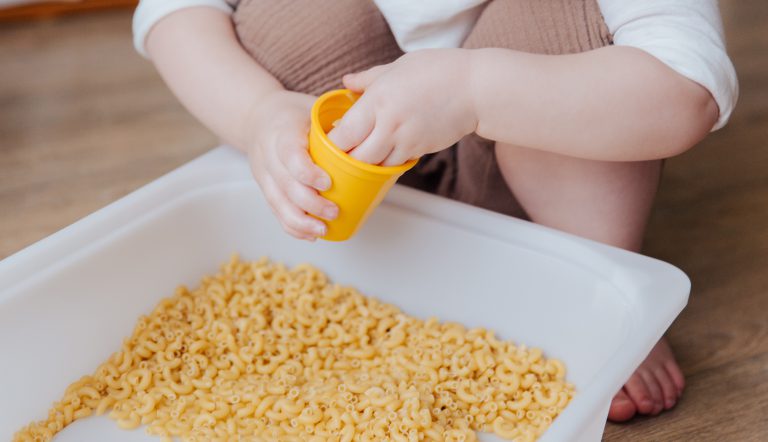 Kind dat sensopathisch aan het spelen is met macaroni